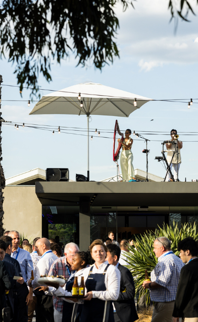 Carousel Corporate Event: Waiters gracefully carry wine while a live band mesmerises with the enchanting sounds of a harp and trumpet