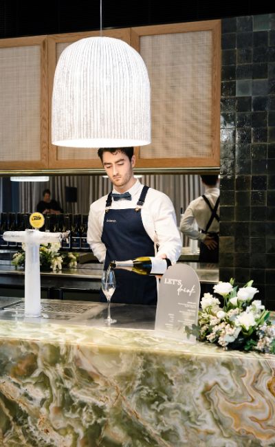 Skilled caterer pouring wine into a glass with one hand behind back, adding elegance to the event