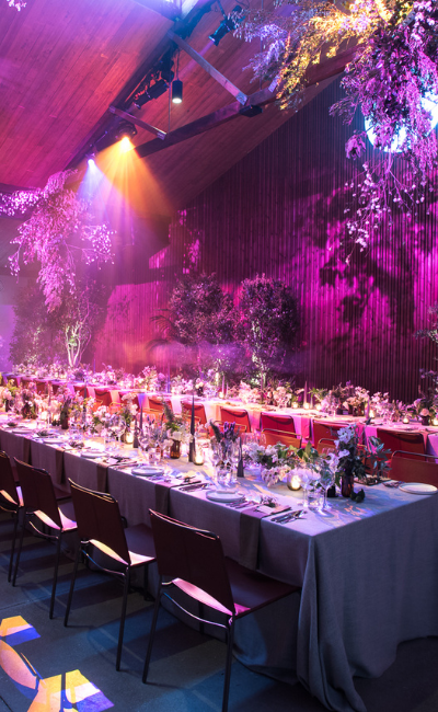 Table setting at Half Acre venue, highlighted by neon lighting, with lush plants in the background, creating a stylish and vibrant ambiance