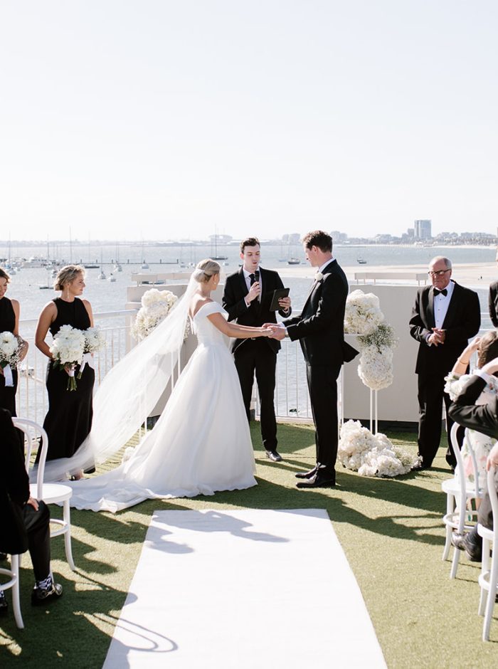 Beachside wedding at Harbour Room, with the bride and groom exchanging heartfelt vows, capturing the romantic essence of their special day