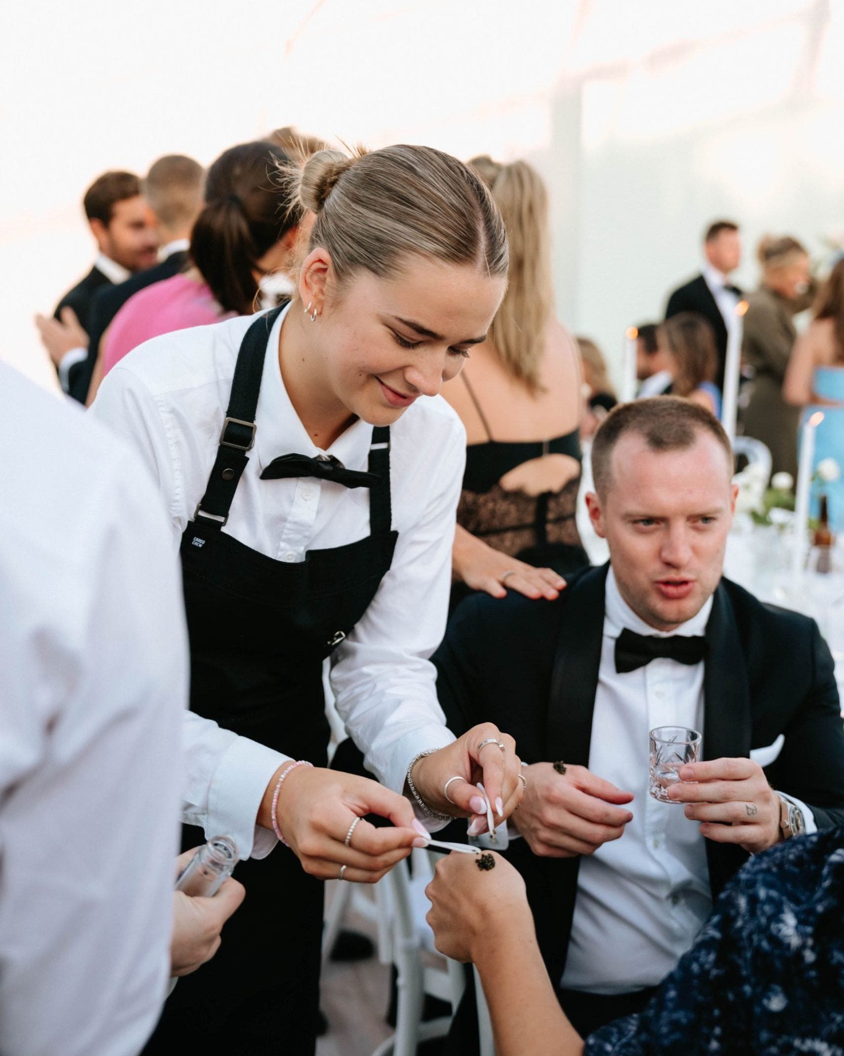 Waitress carefully presenting a caviar canapé at a corporate event, showcasing delicate finger food.